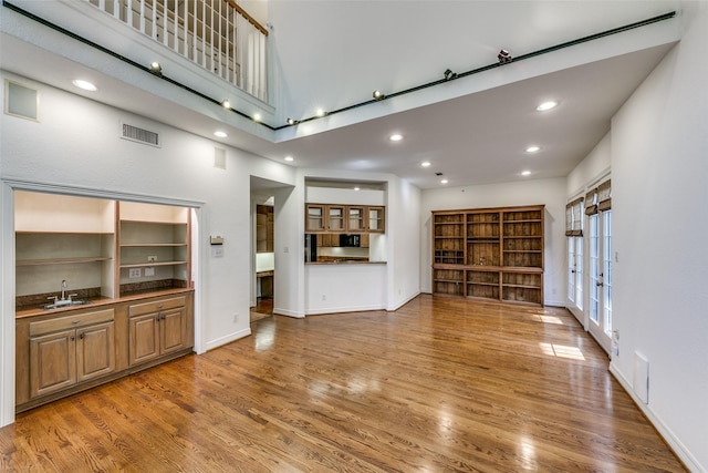 unfurnished living room with sink, a high ceiling, and hardwood / wood-style flooring