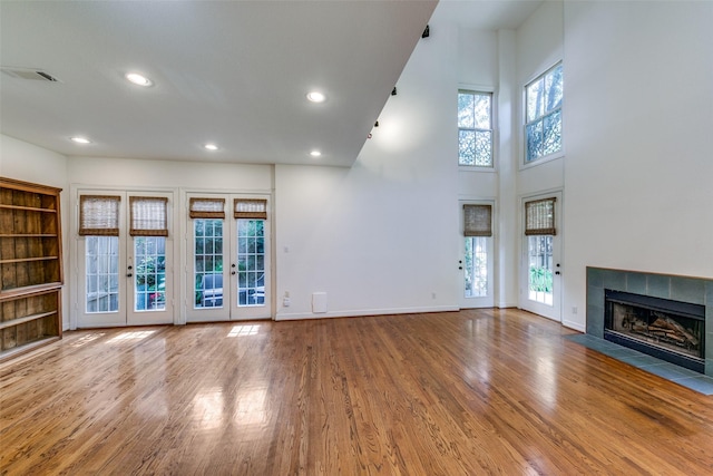 unfurnished living room with hardwood / wood-style floors, french doors, and a healthy amount of sunlight