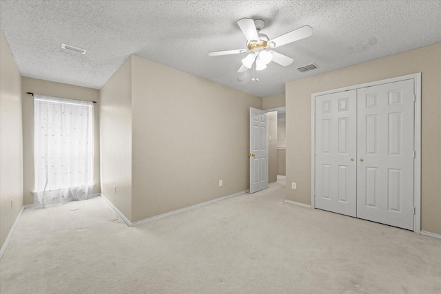 unfurnished bedroom featuring ceiling fan, light carpet, a closet, and a textured ceiling