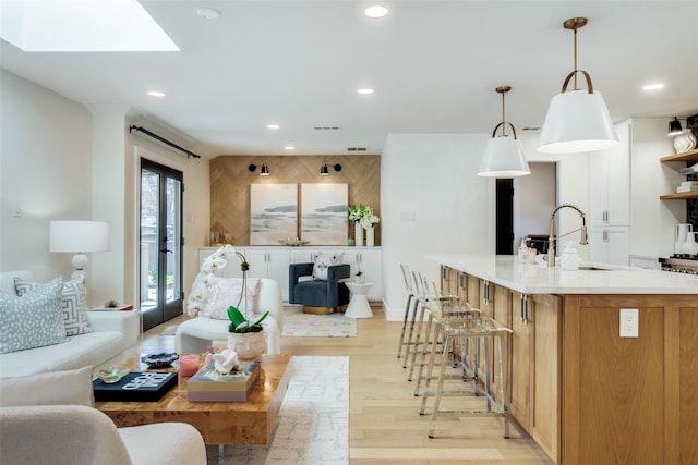 living room featuring a skylight, sink, and light hardwood / wood-style flooring