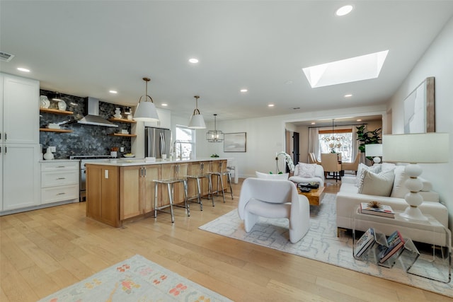 living room featuring a skylight, an inviting chandelier, and light hardwood / wood-style floors