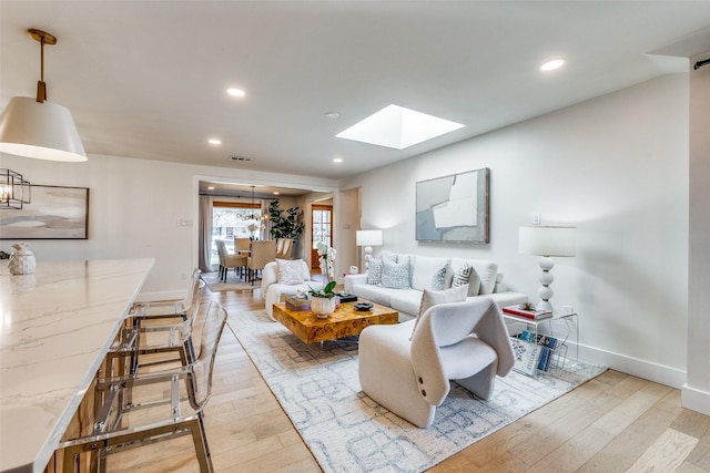 living room featuring light hardwood / wood-style floors and a skylight