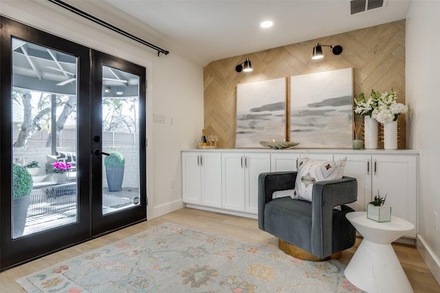 living area with light hardwood / wood-style floors and french doors