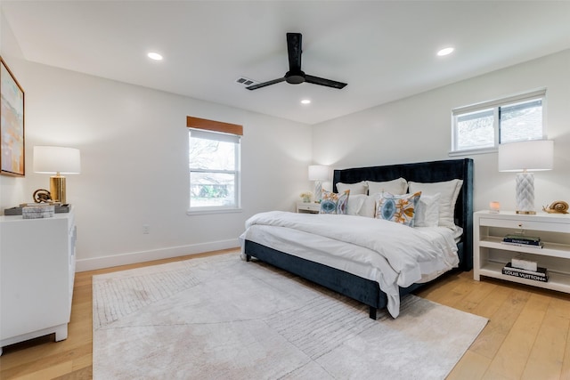 bedroom featuring ceiling fan, multiple windows, and light hardwood / wood-style flooring