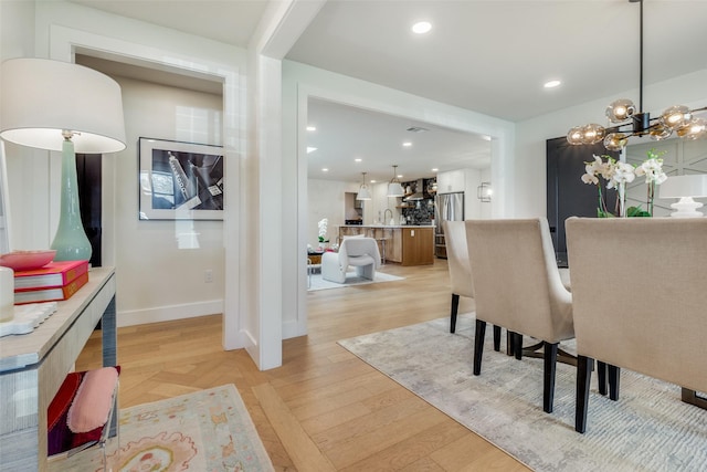 dining area with light hardwood / wood-style floors and a chandelier