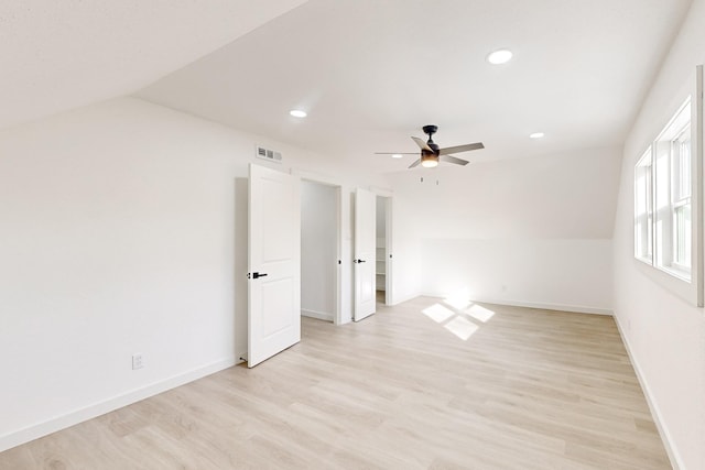 empty room with ceiling fan, vaulted ceiling, and light hardwood / wood-style flooring