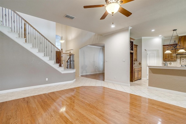 unfurnished living room with light tile patterned flooring, ceiling fan, and ornamental molding