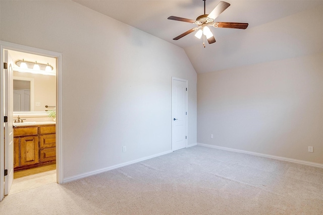 unfurnished bedroom featuring light carpet, sink, vaulted ceiling, ceiling fan, and ensuite bathroom