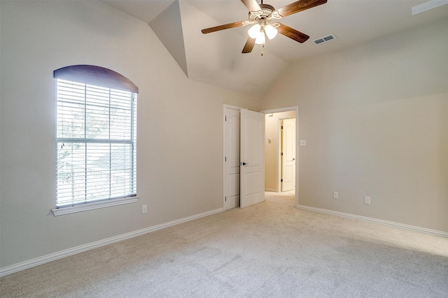 carpeted empty room featuring vaulted ceiling, ceiling fan, and plenty of natural light