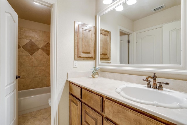 full bathroom featuring toilet, tile patterned flooring, tiled shower / bath combo, and vanity