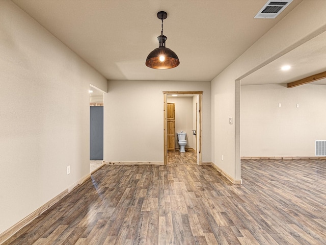 unfurnished room with baseboards, wood finished floors, and visible vents