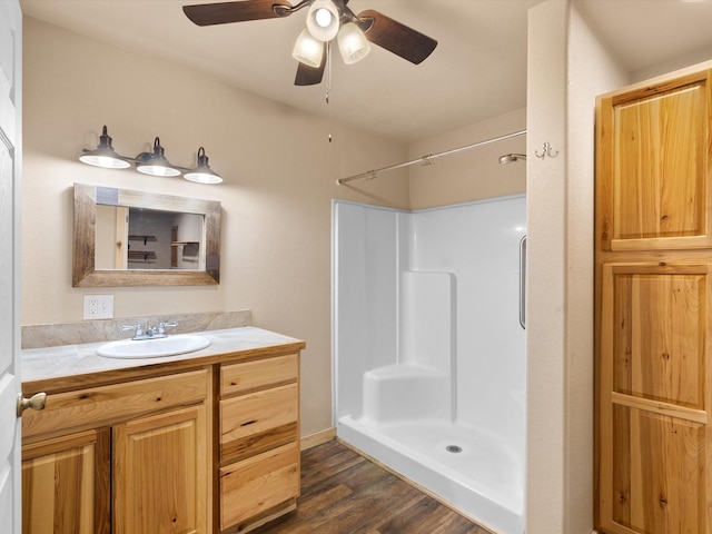 bathroom with a shower, a ceiling fan, wood finished floors, and vanity