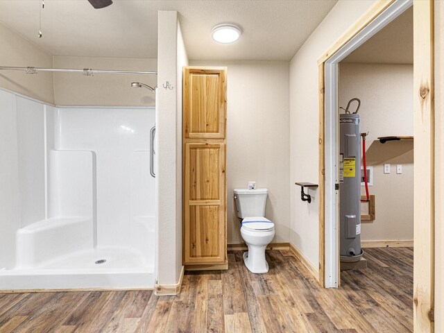 bathroom featuring a stall shower, wood finished floors, baseboards, toilet, and water heater