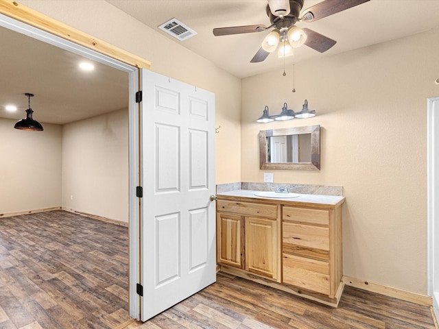 bathroom featuring ceiling fan, vanity, baseboards, wood finished floors, and visible vents