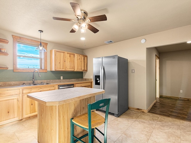 kitchen featuring visible vents, a sink, stainless steel fridge with ice dispenser, light countertops, and light brown cabinets