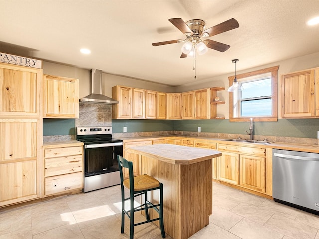 kitchen featuring stainless steel appliances, pendant lighting, a kitchen island, wall chimney exhaust hood, and sink