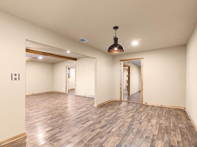 spare room featuring hardwood / wood-style flooring and beam ceiling