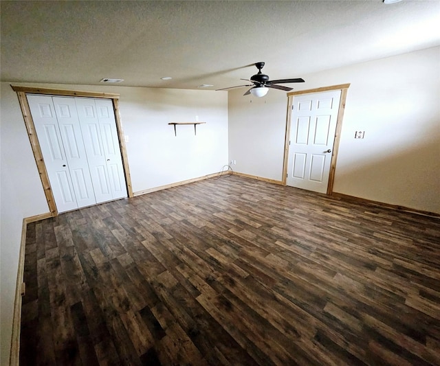 interior space featuring ceiling fan, a textured ceiling, visible vents, dark wood finished floors, and baseboards