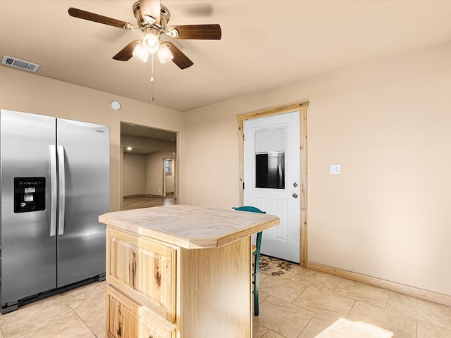 kitchen with ceiling fan, a center island, tile counters, light brown cabinetry, and stainless steel fridge