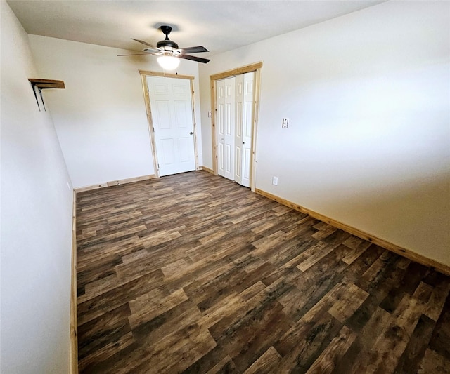 empty room with baseboards, a ceiling fan, and dark wood-style flooring