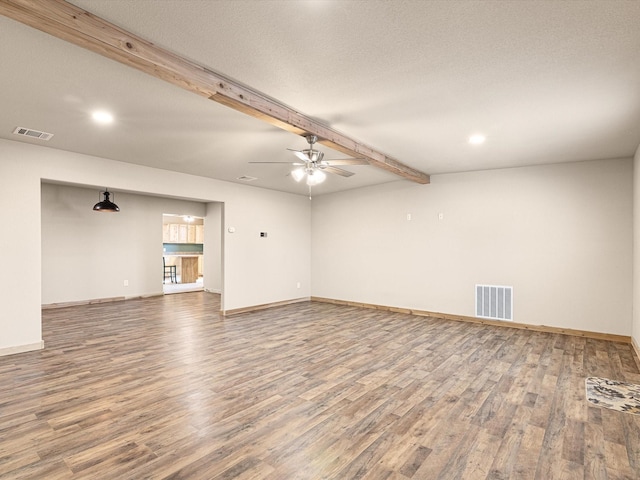 unfurnished living room with a textured ceiling, ceiling fan, wood-type flooring, and beamed ceiling