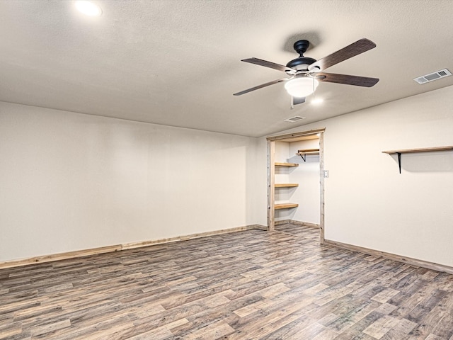 basement with ceiling fan, a textured ceiling, and hardwood / wood-style flooring