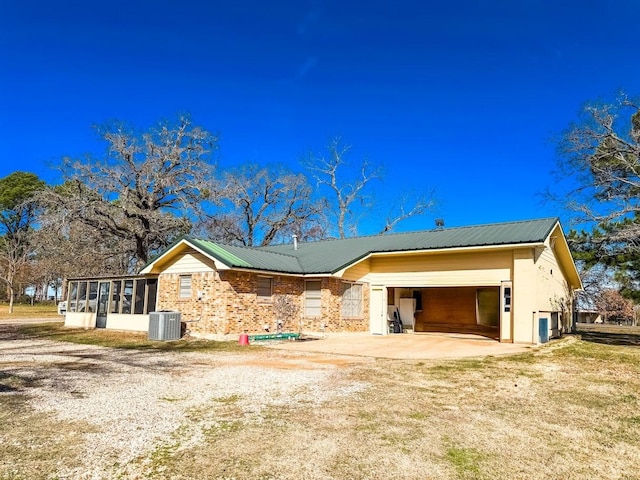 exterior space featuring a garage, a sunroom, and central air condition unit