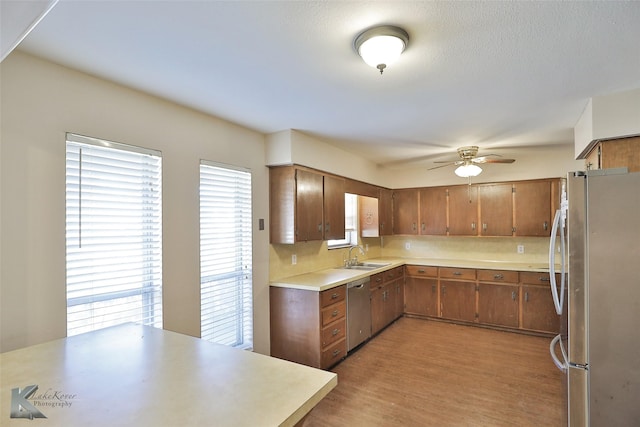 kitchen with ceiling fan, sink, stainless steel appliances, and light wood-type flooring