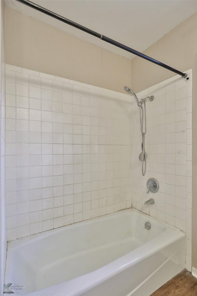 bathroom featuring wood-type flooring and tiled shower / bath