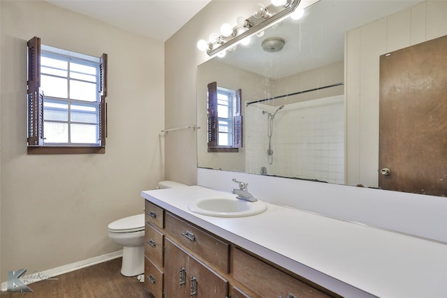 bathroom featuring vanity, toilet, wood-type flooring, and tiled shower