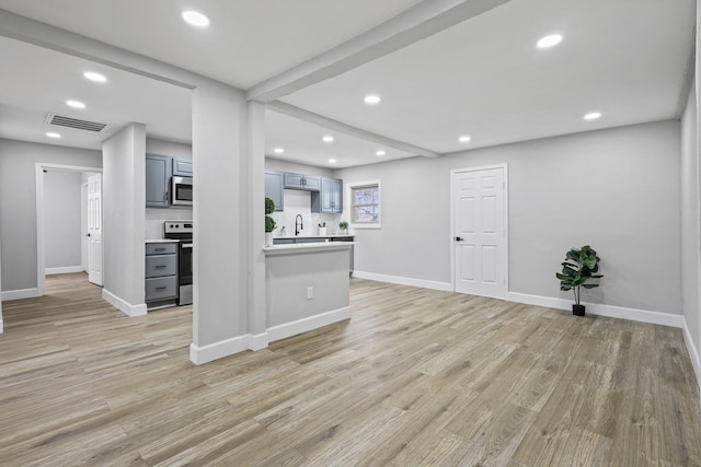 kitchen featuring sink, beam ceiling, light hardwood / wood-style floors, and appliances with stainless steel finishes