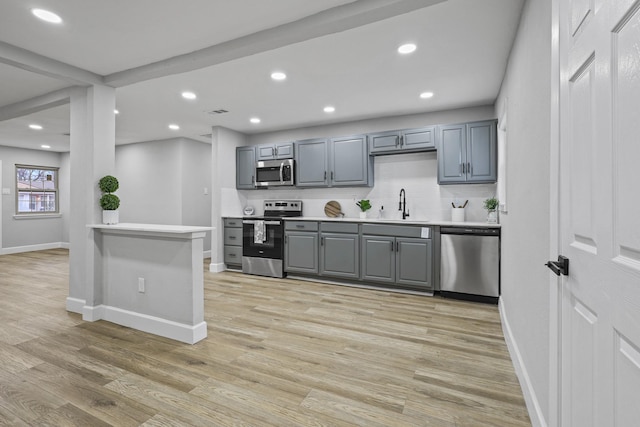 3832 Stateoak Dr, Dallas, TX 75241 - kitchen with stainless steel appliances, gray cabinetry, a sink, baseboards, and light wood finished floors