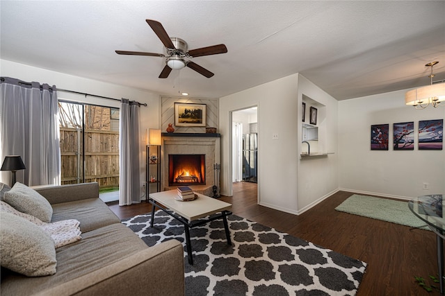 living room with ceiling fan, dark hardwood / wood-style floors, a tile fireplace, and a textured ceiling