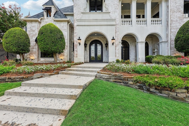 view of exterior entry featuring a balcony and french doors