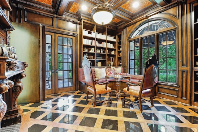 living area featuring built in shelves, french doors, wooden walls, ornamental molding, and coffered ceiling