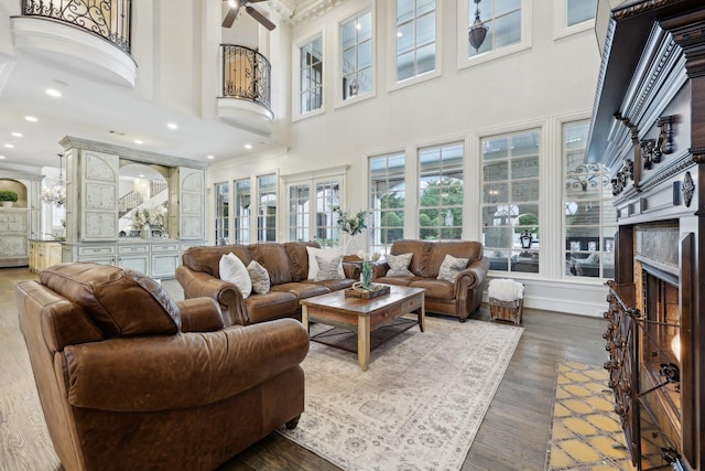 living room featuring ceiling fan, a high ceiling, and dark hardwood / wood-style flooring