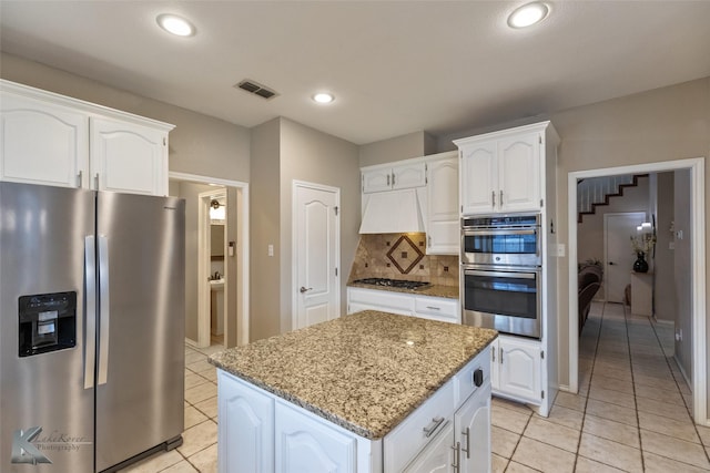 kitchen with decorative backsplash, white cabinets, stainless steel appliances, and stone counters