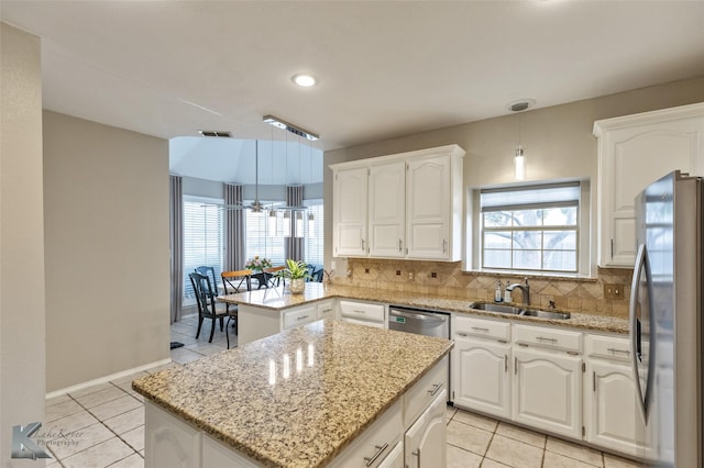 kitchen with stainless steel appliances, hanging light fixtures, a kitchen island, white cabinets, and sink