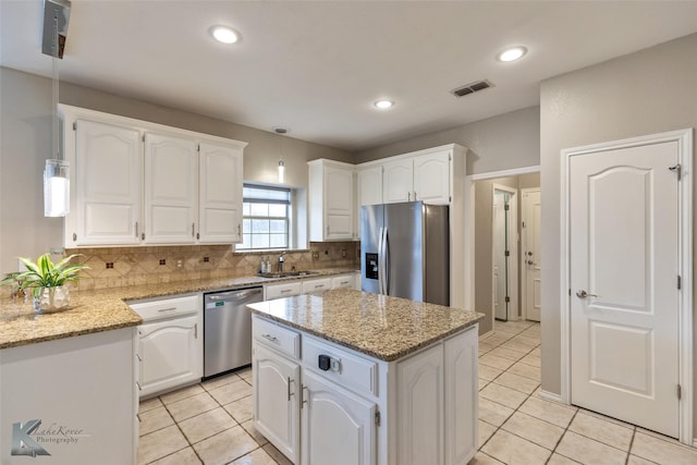 kitchen featuring a kitchen island, sink, stainless steel appliances, white cabinets, and light stone counters