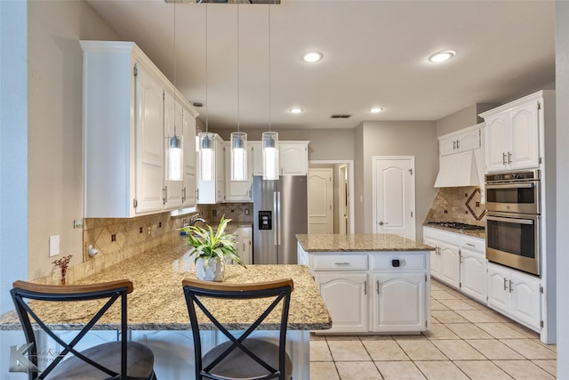 kitchen featuring stainless steel appliances, decorative backsplash, white cabinetry, and a center island