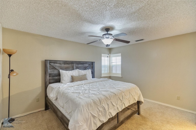 bedroom featuring ceiling fan, light colored carpet, and a textured ceiling