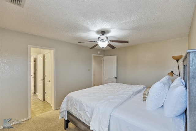 bedroom featuring ceiling fan, light colored carpet, and a textured ceiling