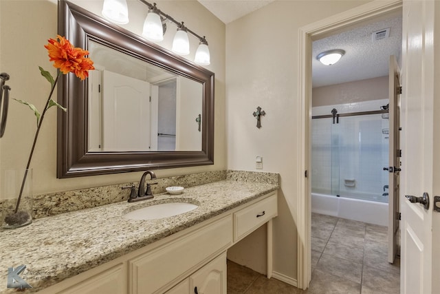 bathroom with a textured ceiling, enclosed tub / shower combo, vanity, and tile patterned flooring