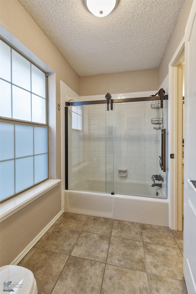 bathroom featuring a textured ceiling, enclosed tub / shower combo, and a healthy amount of sunlight