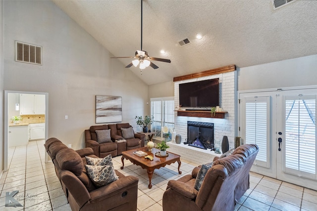 living room featuring light tile patterned flooring, a textured ceiling, a healthy amount of sunlight, and a fireplace