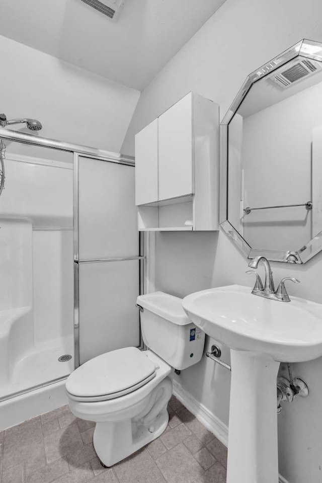 bathroom with toilet, sink, and a shower with shower door