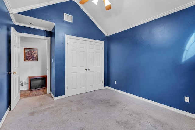 unfurnished bedroom featuring ceiling fan, a closet, lofted ceiling, light colored carpet, and crown molding