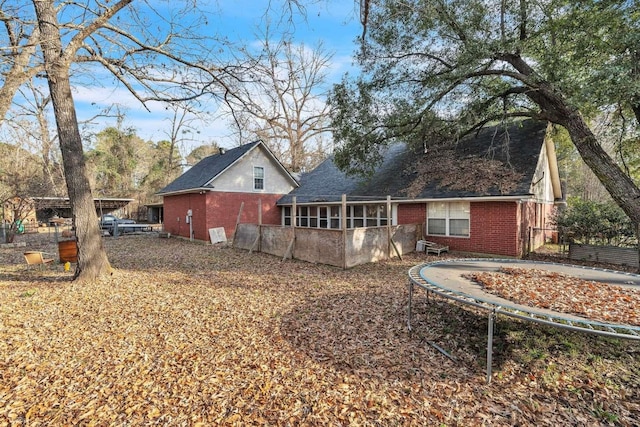 back of property featuring a trampoline and a sunroom