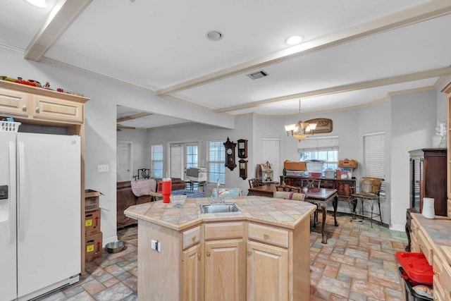 kitchen featuring a notable chandelier, sink, a kitchen island with sink, light brown cabinetry, and white fridge with ice dispenser