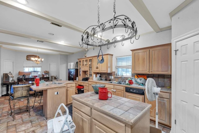 kitchen with a center island, tile counters, a healthy amount of sunlight, decorative backsplash, and an inviting chandelier